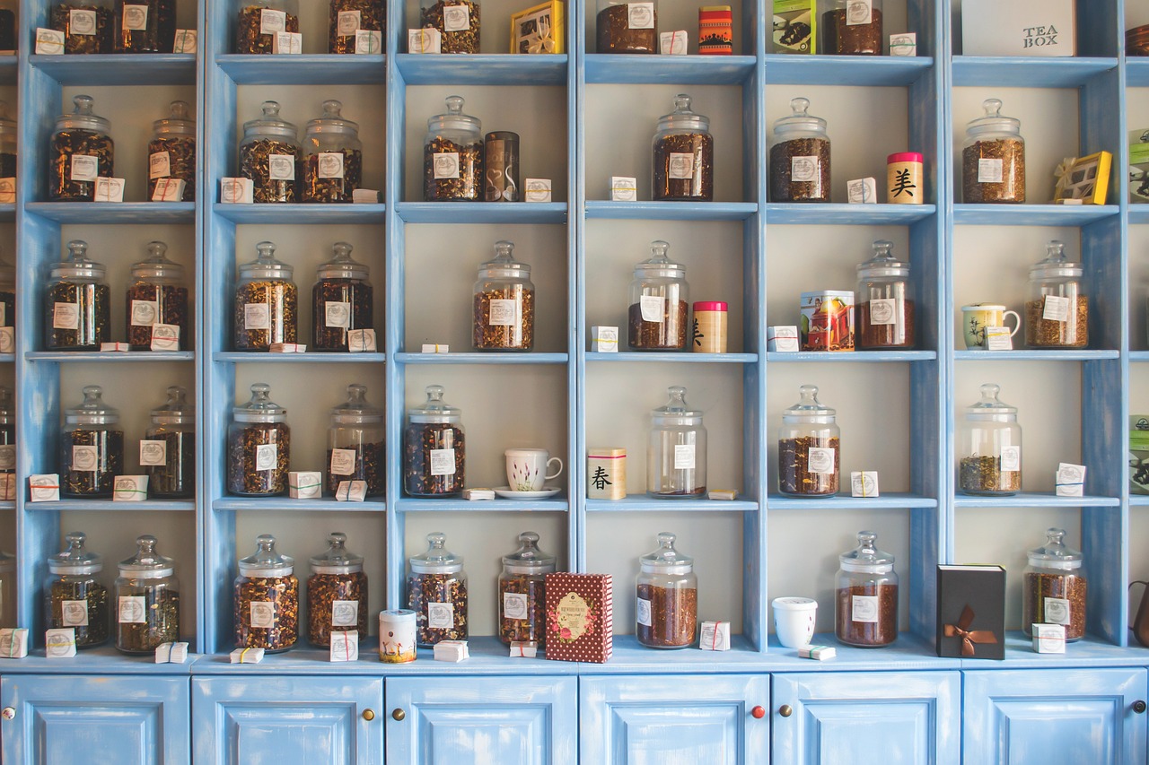 Pale blue shelves lined with glass jars of loose leaf tea, tins and teacups